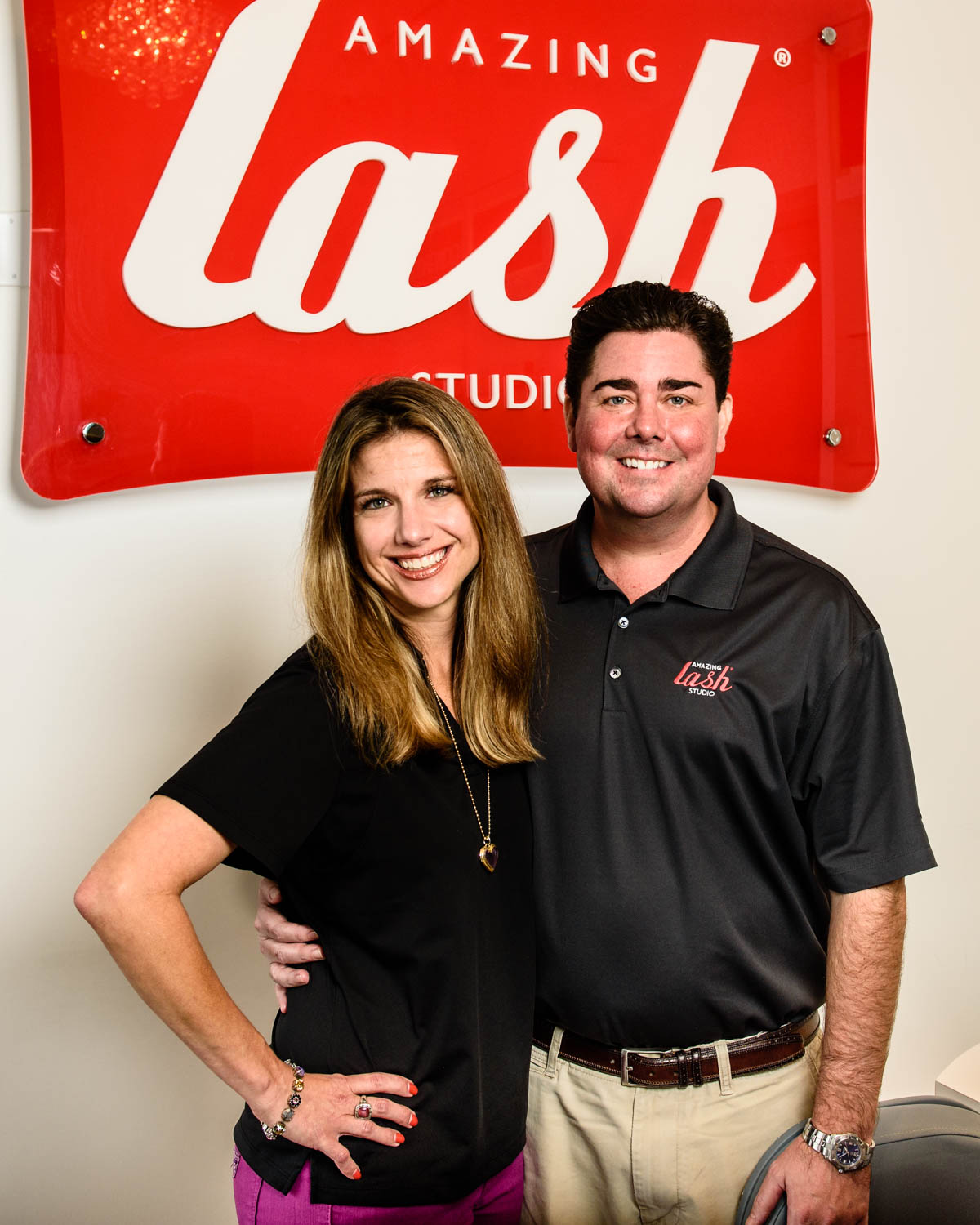 Amazing Lash Franchise owners posing in front of lash logo 